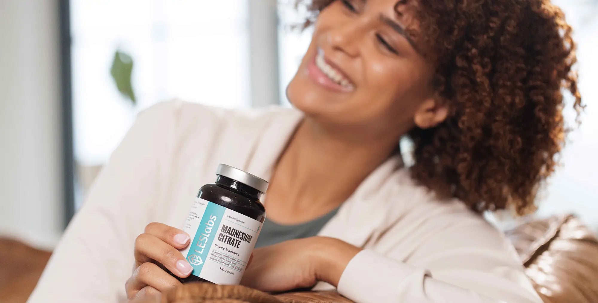 Woman holding a bottle of Magnesium Citrate bottle in a casual setting