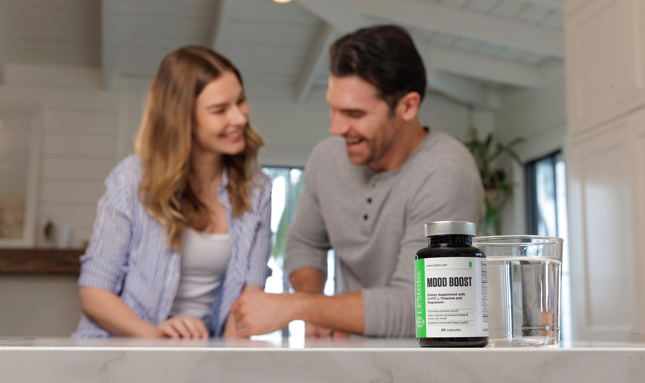 Photo of happy man and woman with mood boosting supplement on kitchen counter.